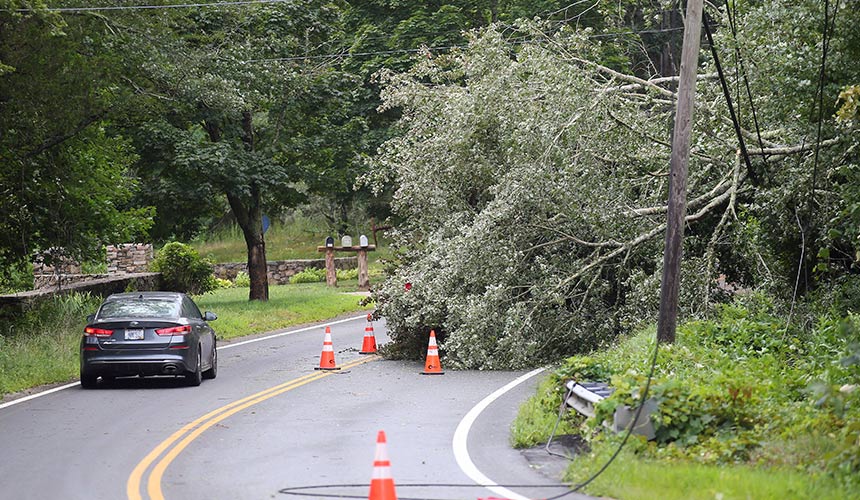 Sebuah kenderaan mengelak pokok tumbang yang mengenai kabel tenaga elektrik di Route 138, South Kingstown, Rhode Island, 22 Ogos, 2021. (Foto AP)