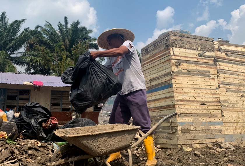 Malizi sedang giat membersihkan kawasan rumah selepas banjir. - Foto Astro AWANI