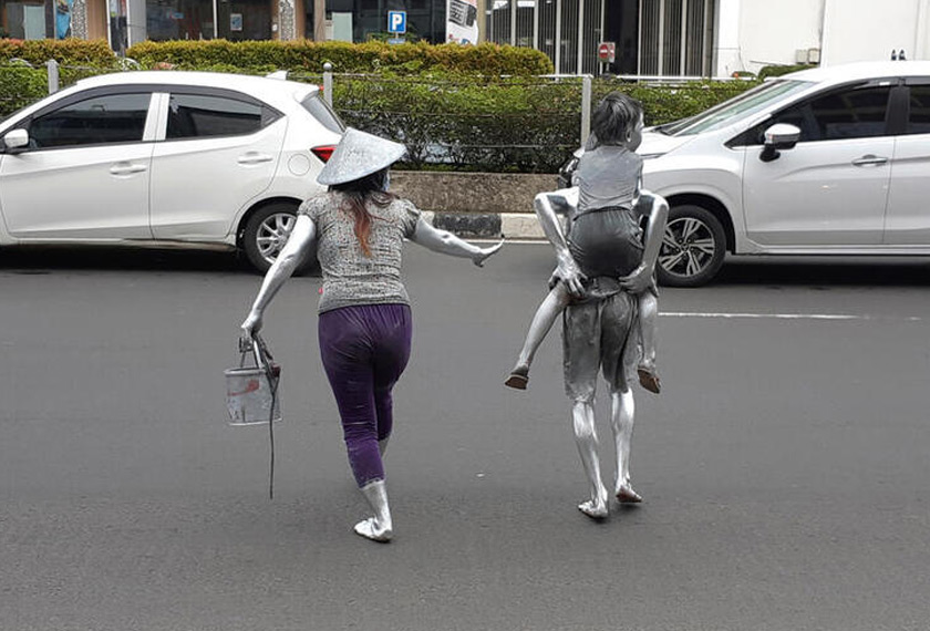 Puryanti, with her nephew Raffi and son Faldo 5, covered in silver paint as part of their act to make a living, cross a street in Depok, on the outskirts of Jakarta, Indonesia. REUTERSpic