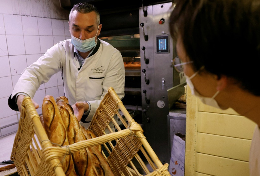 Reydellet, wearing a protective face mask, installs freshly-baked baguettes in a wicker basket. REUTERSpic