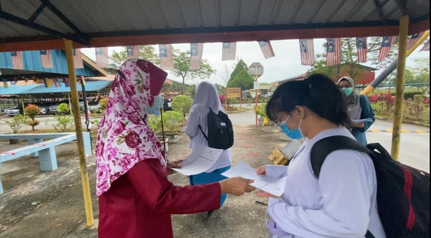 Para guru menyerahkan borang deklarasi saringan COVID-19 kepada setiap calon SPM.