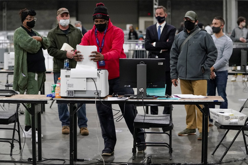 A Fulton County election worker puts absentee ballots in a scanner as election observers look on, at the Georgia World Congress Center in Atlanta, Georgia, US, Jan 5, 2021. REUTERSpic