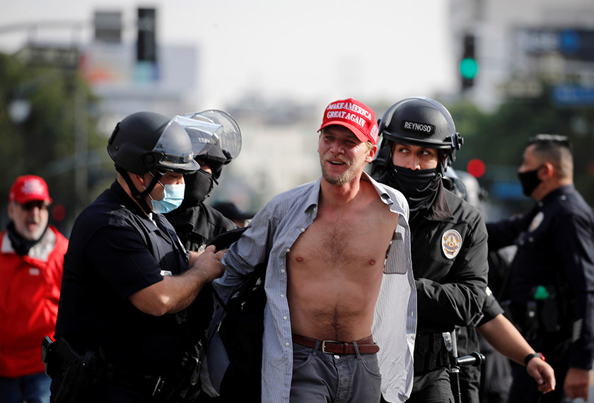 A supporter of U.S. President Donald Trump wearing a Make America Great Again (MAGA) hat reacts upon getting detained by the police while protesting in Los Angeles, California, U.S., January 6, 2021. REUTERS/Mike Blake