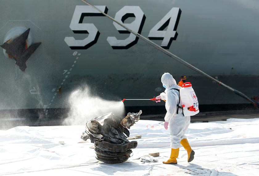 A member of Indonesia Red Cross sprays disinfectant on a piece of debris retrieved from the sea, believed to be from the turbine of Sriwijaya Air flight SJ182, which crashed to the sea, in Jakarta, Indonesia, January 11, 2021. REUTERS/Ajeng Dinar Ulfiana