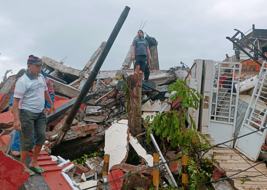 Residents inspect earthquake-damaged houses in Mamuju, West Sulawesi, Indonesia, Friday, Jan. 15, 2021. A strong inland and shallow earthquake hit eastern Indonesia early Friday causing people to panic in parts of the country's Sulawesi island and run to higher ground. (AP Photo/Rudy Akdyaksyah)