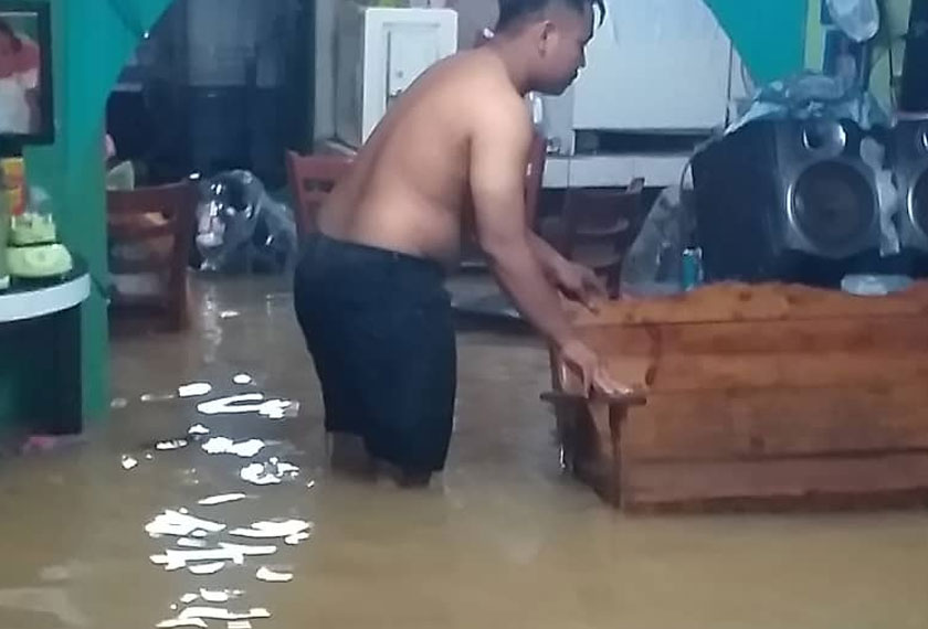Kelihatan mangsa banjir di Putatan mengalihkan peralatan elektrik selepas rumah mereka dinaiki air.