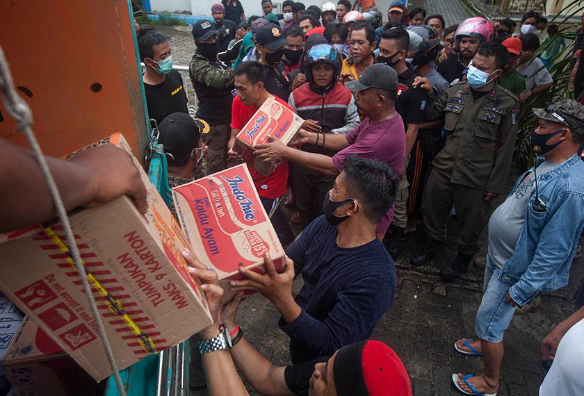 People who are affected by an earthquake queue up for food aid in Mamuju, West Sulawesi, Indonesia, Sunday, Jan. 17, 2021. (AP Photo/Yusuf Wahil)