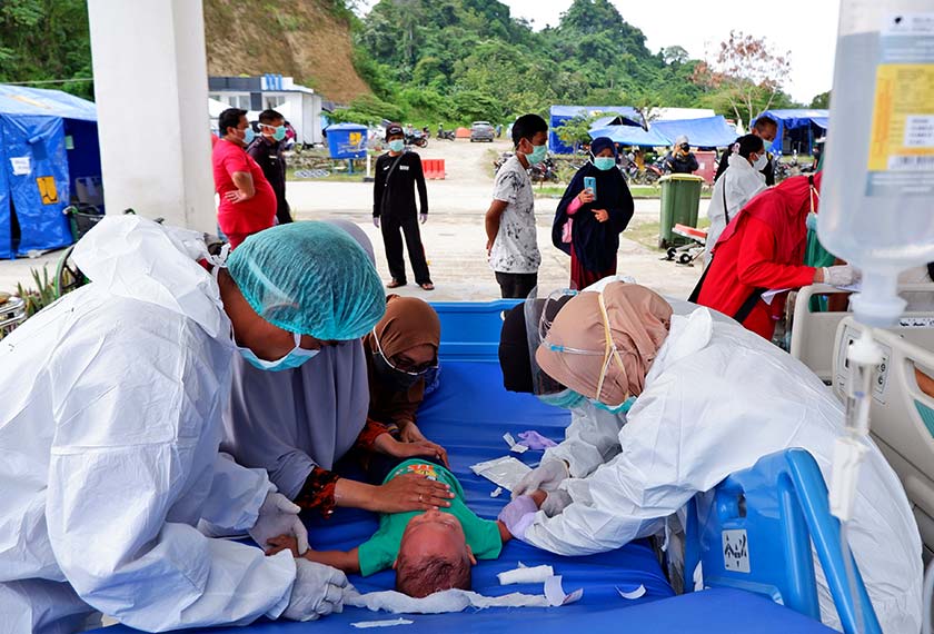 A child receives medical treatment at the entrance hallway of a hospital as patients are treated outside amid fears of aftershocks at a hospital affected by an earthquake in Mamuju, West Sulawesi, Indonesia, Sunday, Jan. 17, 2021. (AP Photo/Daeng Mansur)