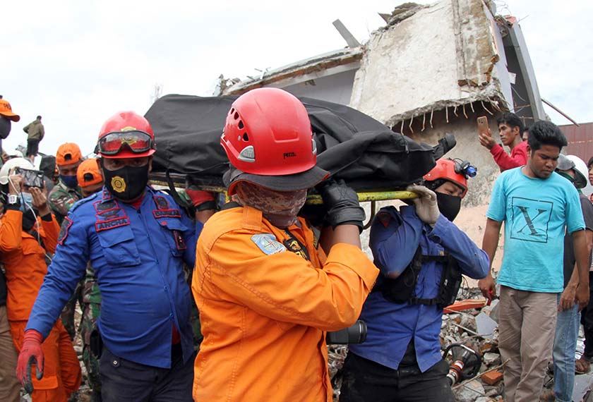Rescuers carry the body of an earthquake victim retrieved from the ruin of a building damaged by an earthquake in Mamuju, West Sulawesi, Indonesia, Saturday, Jan. 16, 2021. (AP Photo/Bamu Saseno)