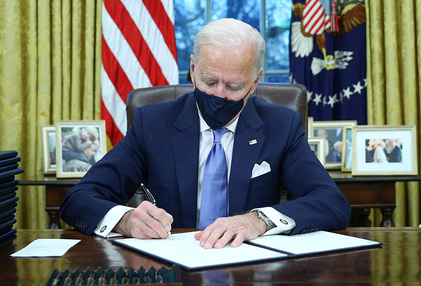 U.S. President Joe Biden signs executive orders in the Oval Office of the White House in Washington, after his inauguration as the 46th President of the United States, U.S., January 20, 2021. REUTERS/Tom Brenner