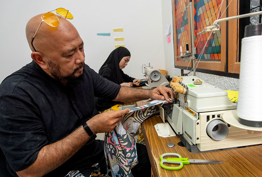 Mohd Rosoliza dan isteri menjahit seluar 'Separuh Rindu' yang ditempah pelanggan. --fotoBERNAMA