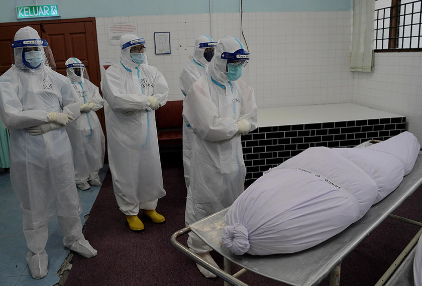 Faizah Hamezah (belakang) bersama rakan setugas melakukan solat jenazah ke atas jenazah pesakit COVID-19 di Jabatan Perubatan Forensik Hospital Sultanah Johor Bahru baru-baru ini. - Gambar BERNAMA