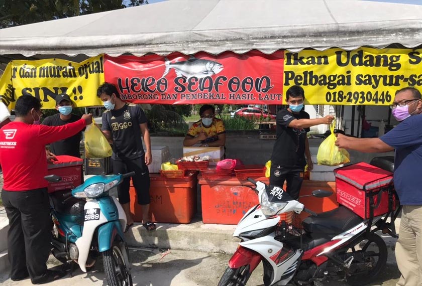 Rijal Fikry (dua dari kanan) menyerahkan pesanan ikan kepada rider yang untuk dihantar kepada pelanggan yang membuat tempahan secara dalam talian. - Foto MEDAC