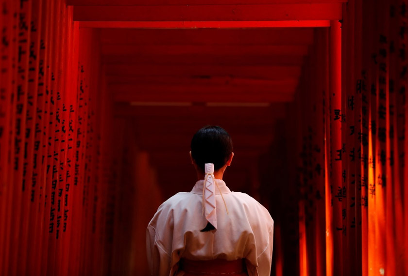 Shouko Totsuka, a Miko also known as a shrine maiden, poses for a photograph as she stands inside the tunnel of Red Torii Gate at the Hie-Jinja Shinto Shrine in Tokyo, Japan. REUTERSpic