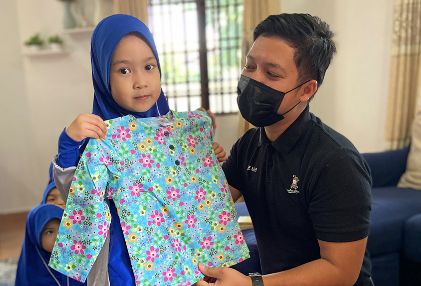 Zaim Izkandar menghadiahkan sepasang baju kurung kepada salah seorang anak yatim.