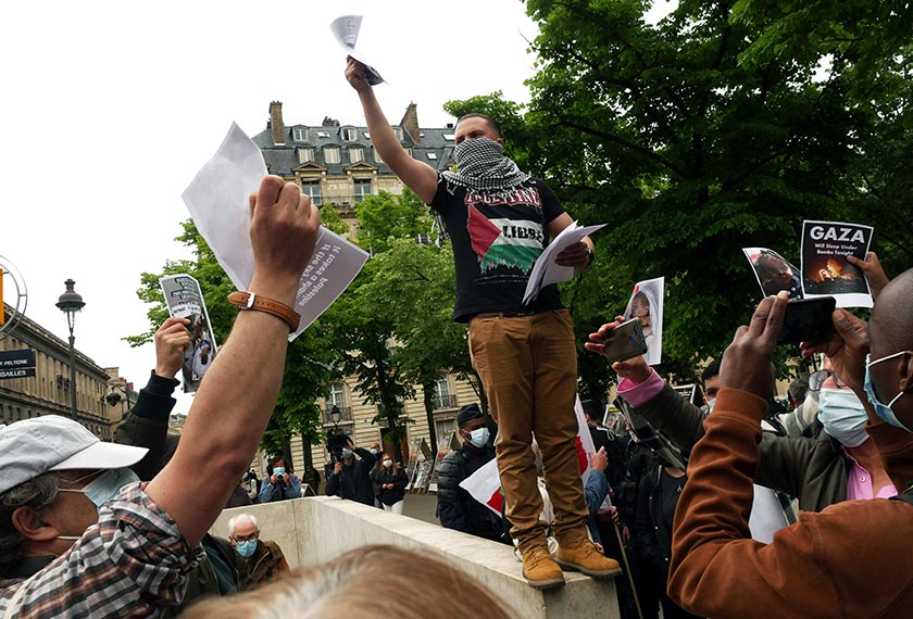 Seorang penunjuk perasaan mengedarkan risalah ketika memprotes serangan udara Israel ke atas Palestin, di Paris, 12 Mei, 2021. (Foto AP)