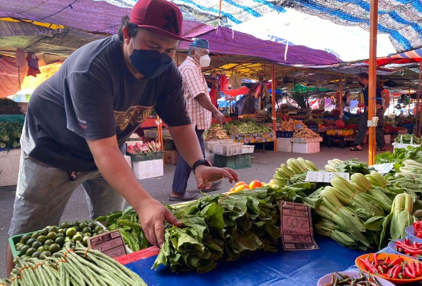Roy (gambar) menyusun sayur-sayuran di Pasar Kubah Ria, Kuching.