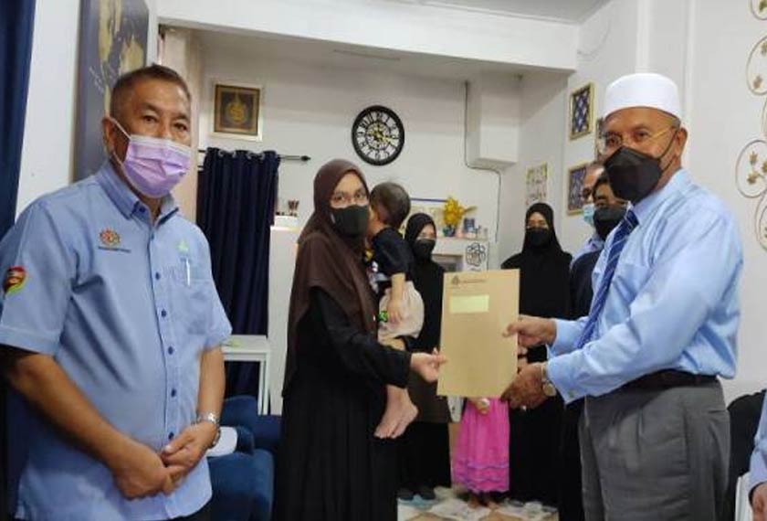 Idris (kanan) menyerahkan cek Perkeso kepada Mahirah sambil disaksikan oleh Zainol (kiri) di rumah Mahirah di Seksyen 14, di sini pada Selasa.  - Foto Sinar Harian