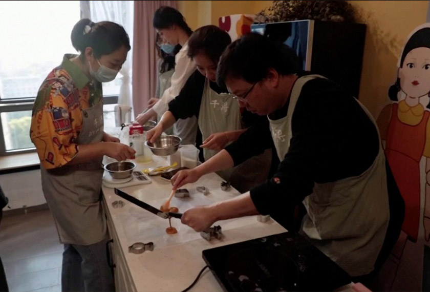 A customer pours biscuit mixture onto baking paper during a session of a South Korean Netflix show Squid Game-themed confection-making event, at a bakery in Beijing, China in this screengrab from a video taken on October 16, 2021. - REUTERS 