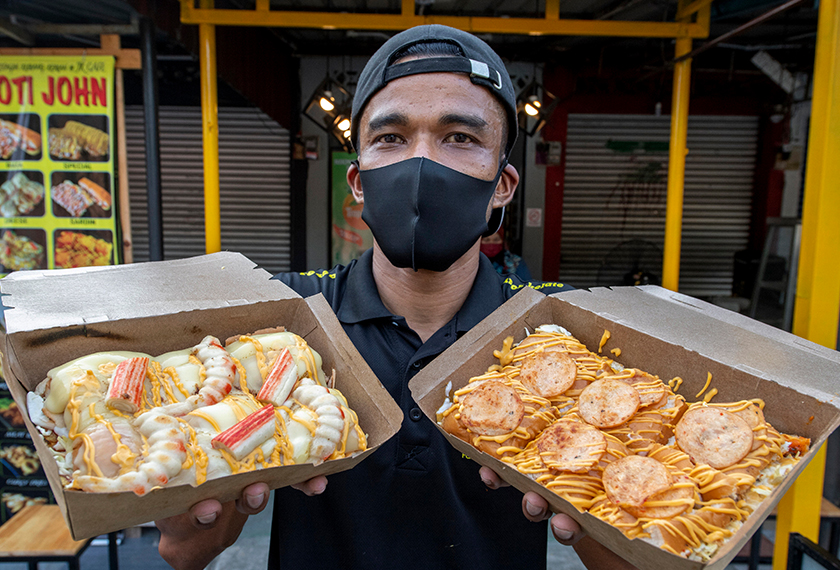 Muhamad Azhar Zainudin, 36, menunjukkan dua variasi roti iaitu pepperoni (kanan) dan seafood yang mendapat permintaan tinggi daripada pelanggan. - Gambar BERNAMA