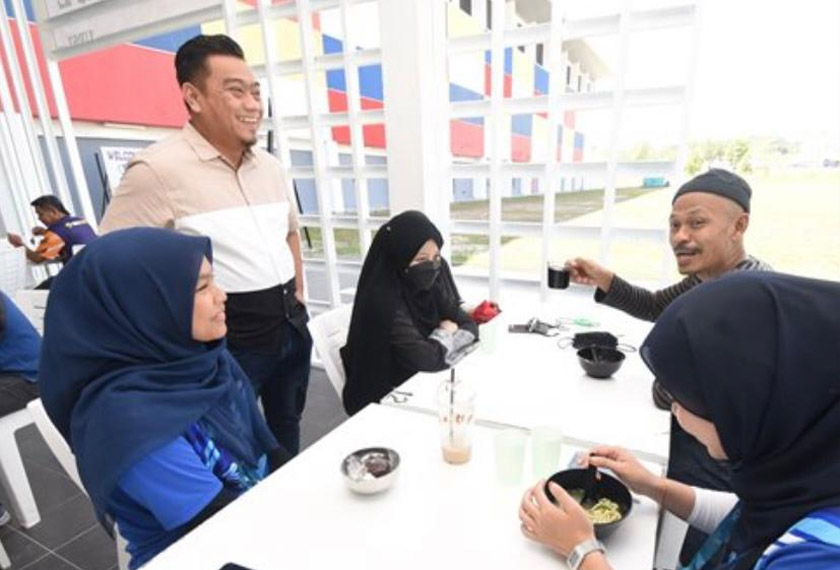 Wan Hairul Azuwan (berdiri) melayan pelanggan yang berkunjung ke kafenya. - Astro AWANI