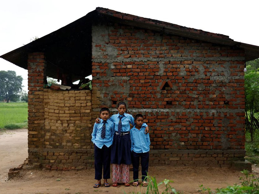 Parwati Sunar, 27, and her sons, Resham Sunar, 11, and Arjun Sunar, 7, pose for a picture after getting dressed for school, outside their house in Punarbas, Kanchanpur district, southwest Nepal. - REUTERS