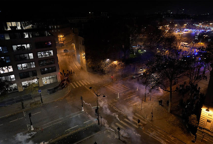 Kelihatan gas pemedih mata dilepaskan berdekatan Arc de Triomphe dan jalan Champs Elysees di Paris ketika penyokong Perancis meraikan kemenangan pasukan negara dalam separuh akhir Piala Dunia, 14 Dis 2022. (Foto AP)