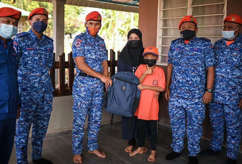   Pengarah Angkatan Pertahanan Awam Kedah, Awang Askandar Ampuan Yaacub menyampaikan sumbangan persekolahan kepada Muhammad Haziq Mohd Asyraf. - Bernama