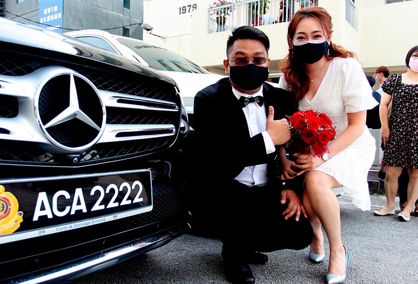 Wong Chung Chow, 31, (kanan) dan pasangannya Lew Khai Chen, 26, bergambar kenangan dengan nombor plat kenderaan kesukaan mereka selepas melangsungkan upacara perkahwinan beramai-ramai di Dewan Orang Ramai Chin Woo yang dianjurkan oleh 'Chin Woo Athletic Association' hari ini. - Foto BERNAMA