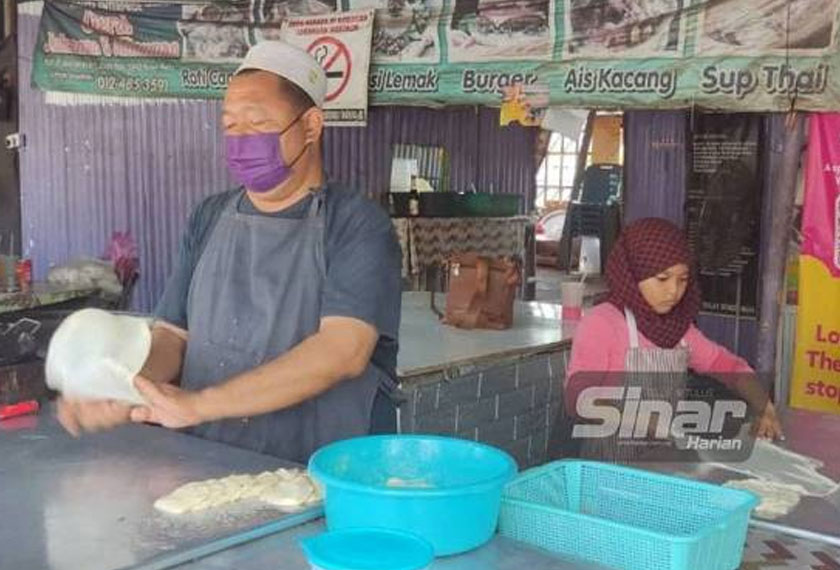Yusna Asna dan bapanya, Ruslin menebar roti canai di gerai makan mereka di berhampiran persimpangan lampu isyarat Balai Baru, Padang Besar pada Ahad. - Foto Sinar Harian