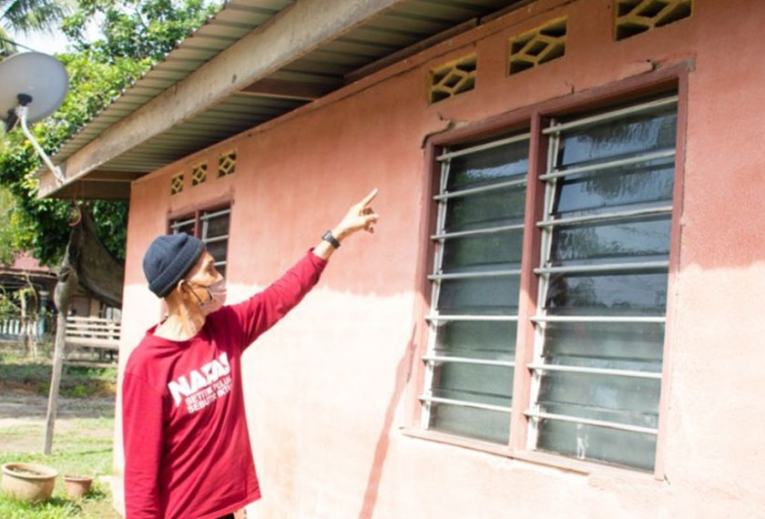 Mohamad Melan menunjukkan kesan keretakan di rumahnya akibat banjir yang melanda Disember lalu. - Foto Astro AWANI