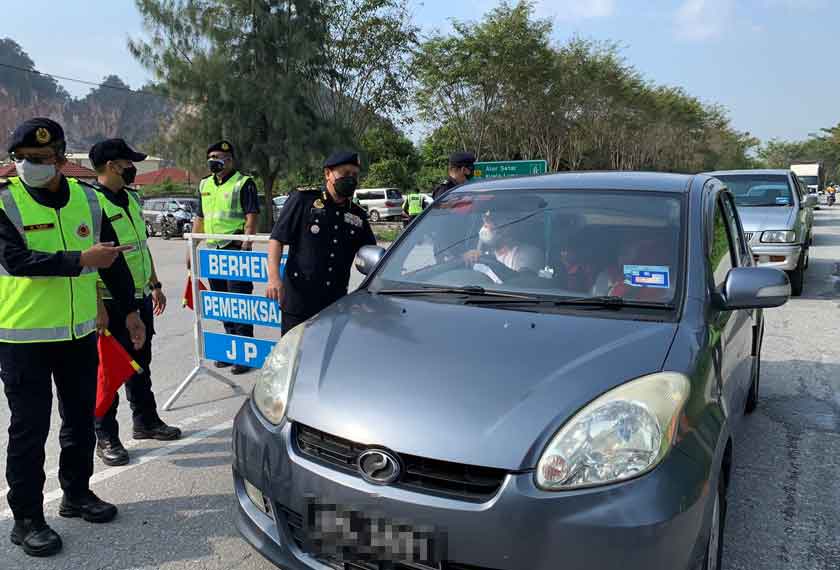 Aedy Fadly Ramli (kanan) menyapa pemandu yang melintasi sekatan jalan raya sempena Op Tahun Baharu Cina 2022 Peringkat Negeri Perak di Kilometer (km) 1, Jalan Simpang Pulai - Cameron Highlands pada Isnin. – Gambar Astro AWANI
