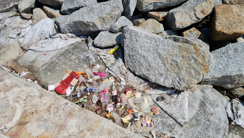Keadaan sampah sarap di sebalik tebing batu di sepanjang pantai.