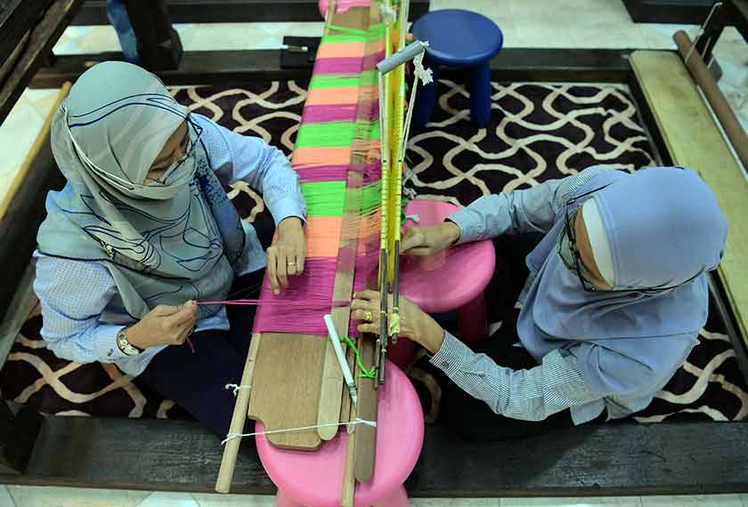 Pembantu Tadbir Jamilah Mustafa (kiri) dan Khalijah Ikhwan melakukan proses mengarat benang ketika ditemui Bernama di Galeri Tenun Johor baru-baru ini. --fotoBERNAMA