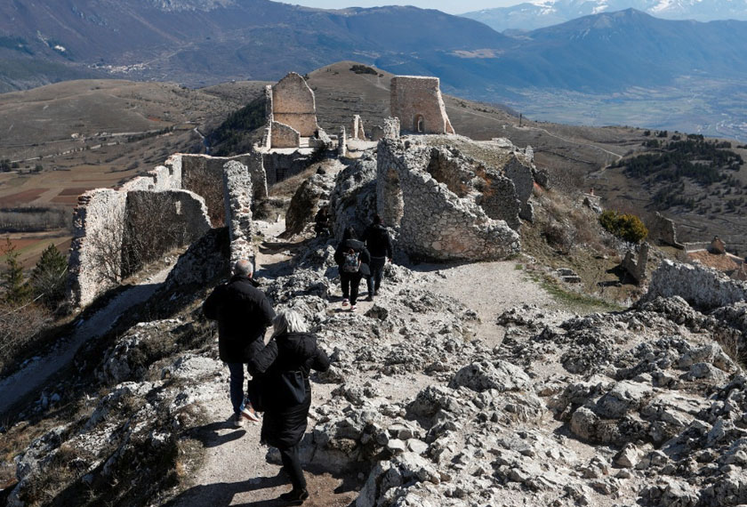 Tourists walk through the ruins of the Rocca Calascio castle situated 1410 metres above sea level, as the sun rises in the small village of Rocca Calascio, Italy. - REUTERS
