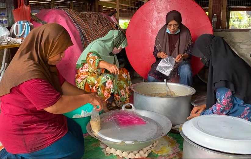 Golongan wanita bertungkus lumus membungkus juadah (bubur lambuk) untuk diedarkan kepada orang ramai. - Foto/AstroAWANI/HafiziRosli