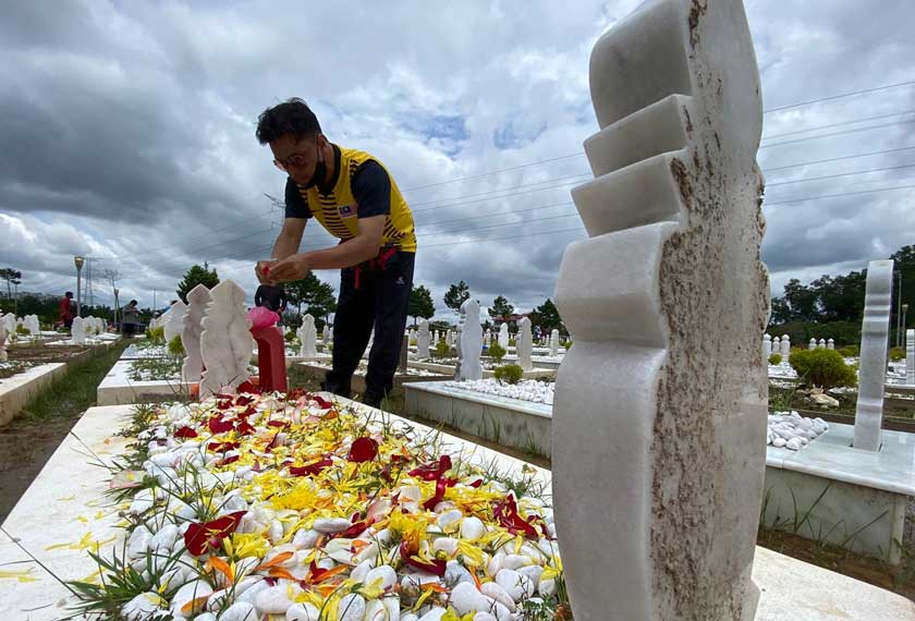 Mohd Taufeq menabur bunga mawar di pusara ibunya. Gambar: Astro AWANI
