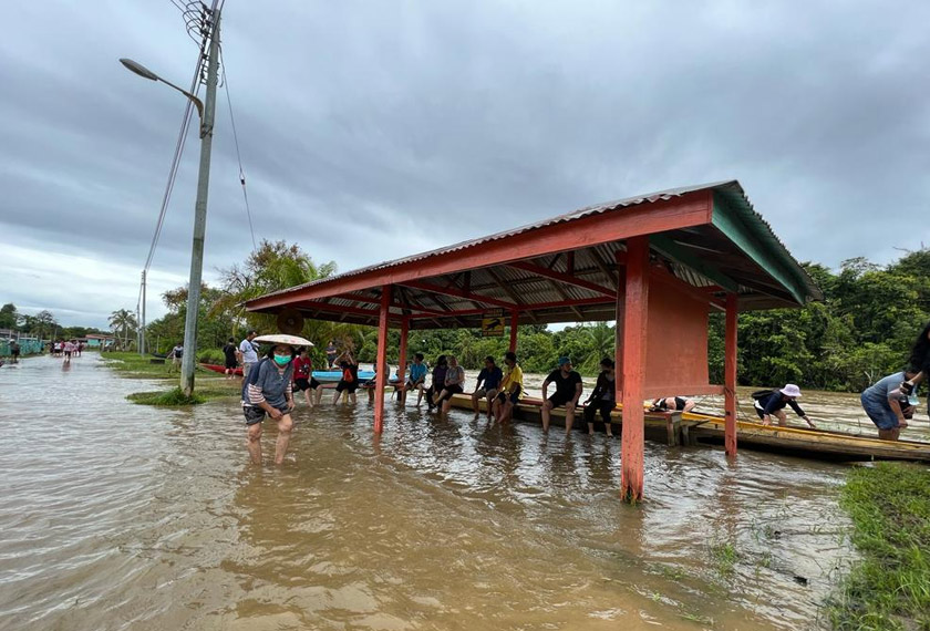Orang ramai yang berteduh di hadapan Pusat Mengundi Sekolah Kebangsaan Long Bemang dalam keadaan jalan yang digenangi air. - Foto JBPM Sarawak