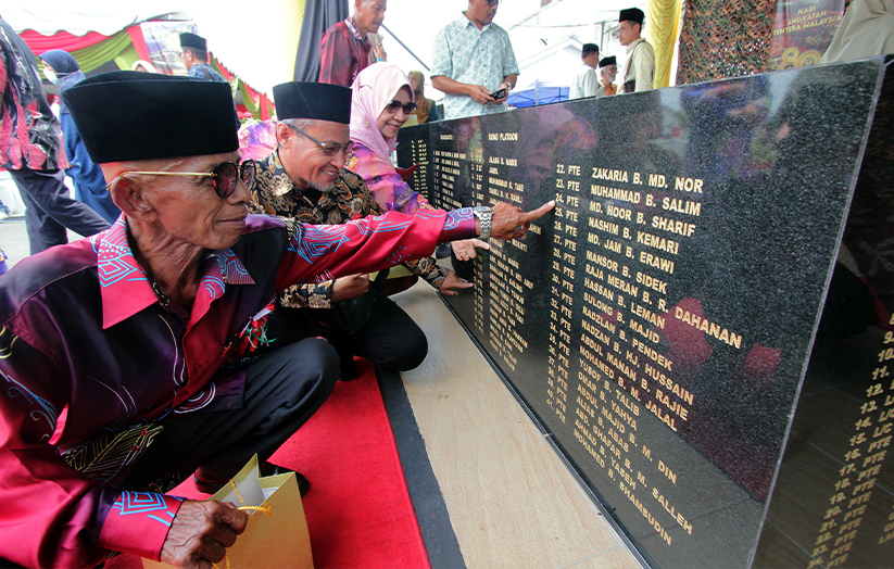 Tiga waris anggota Force 136 (dari kiri) Mat Isa Mat Nor, 72, Hasnizam Osman, 48, dan Ruhani Mansor, 74, menunjukkan nama ayah masing-masing yang terukir pada Tugu Peringatan Force 136 Pahang di Kem Puncak Mas Batalion Ketiga Rejimen 505 Askar Wataniah, Raub, semalam. --fotoBERNAMA