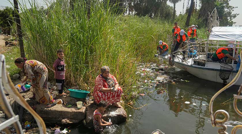 Penduduk tempatan membasuh pinggan mangkuk di sungai ketika para sukarelawan sedang menjalankan kerja-kerja pembersihan di Sungai Nil, Mesir, Kaherah, 29 Sept 2022. (Foto AP)