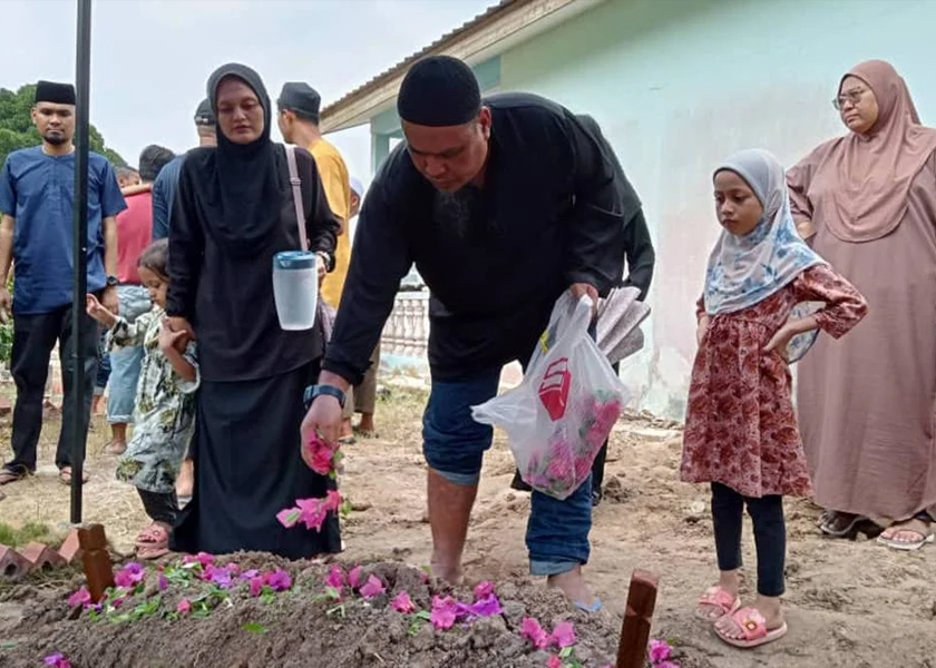 Hermes Latin menabur bunga atas pusara anaknya yang disemadikan di Tanah Wakaf Perkuburan Islam, Kampung Bukit Tunggal, Segamat pada Sabtu.