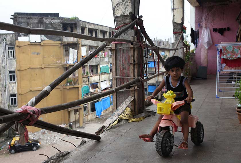Mrunali, 4, Panduram Kharat's daugther rides a tricycle in the corridor outside her home at the Worli dairy quarters building in Mumbai, India. - REUTERS/Francis Mascarenhas