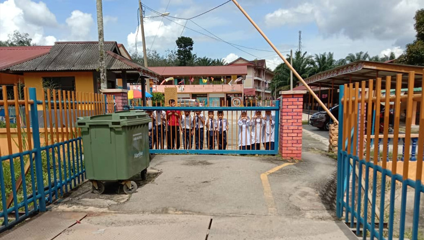 Murid SK Damak melihat dari dalam pintu pagar dan tidak dibenarkan menggunakan jambatan itu. - Astro AWANI