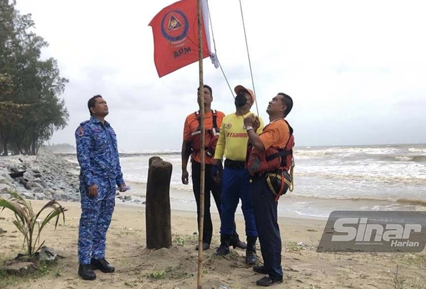 Anggota APM menaikkan bendera sebagai tanda amaran keadaan pantai yang berbahaya.