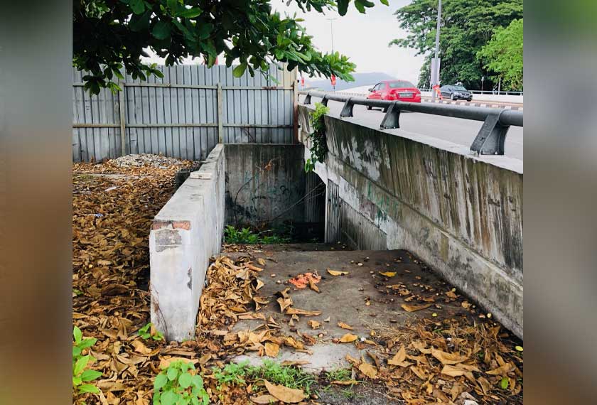 Keadaan terkini di pintu masuk terowong pejalan kaki yang diliputi semak samun dan laluan di dalam yang dipenuhi sampah sarap. - Astro AWANI