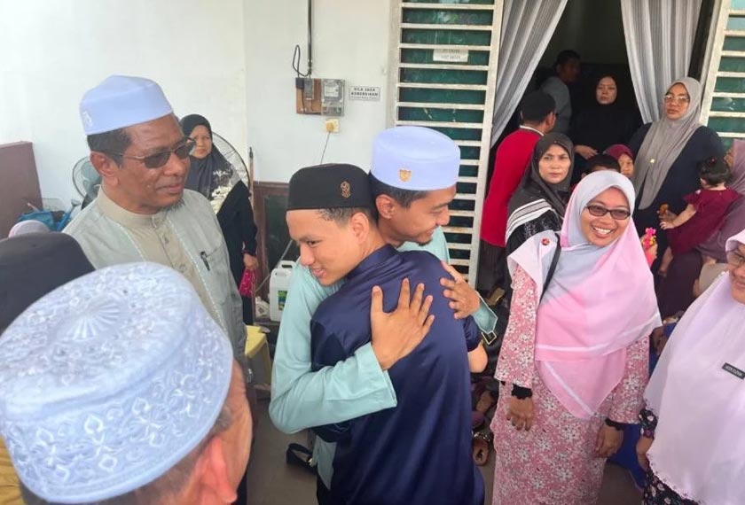 Muhammad Syahril (tengah) yang dipeluk Mohd Syahir di rumahnya pada Ahad. - Foto Sinar Harian