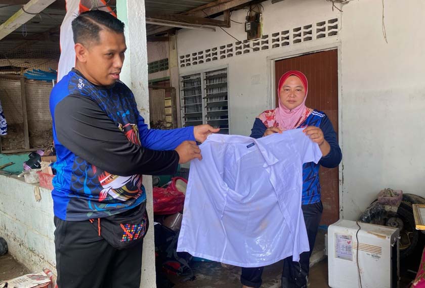 Ainul Azliany menunjukkan pakaian seragam sekolah anaknya yang musnah akibat banjir.- Foto Astro AWANI