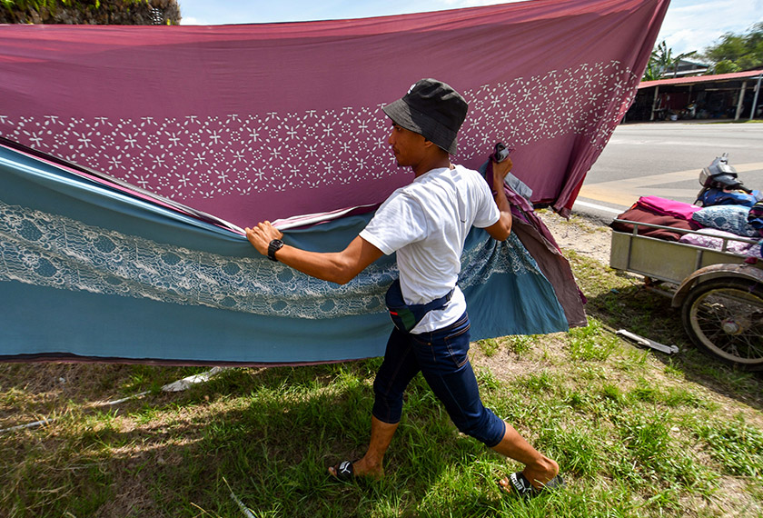 Pekerja batik Muhd Hilmi Abdullah mengangkat kain batik yang sudah dikeringkan, di Kampung Badang, Kota Bharu. --fotoBERNAMA