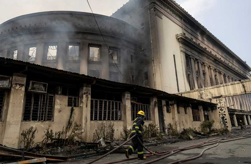 A firefighter pulls a hose to douse the burning Manila Central Post Office building after a massive fire, in Manila, Philippines, May 22, 2023. REUTERS