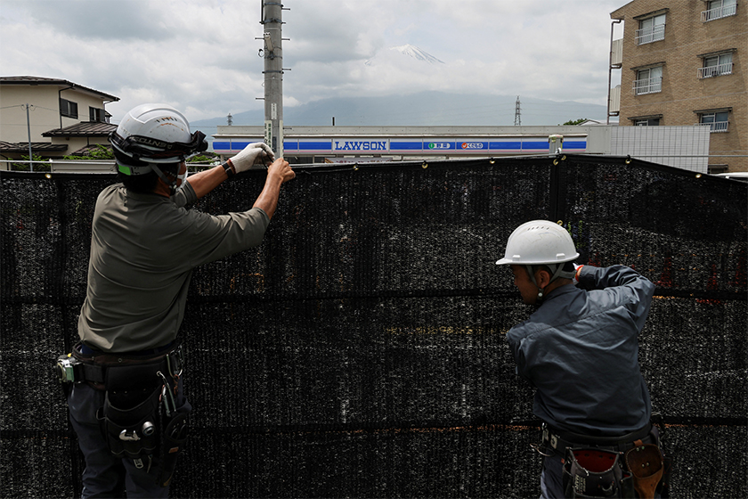 Workers erect a barrier to block the view of a popular Mount Fuji photo spot, near a convenience store in Fujikawaguchiko town, Yamanashi prefecture, Japan. - REUTERS